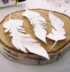 Paper feathers on wood tree section